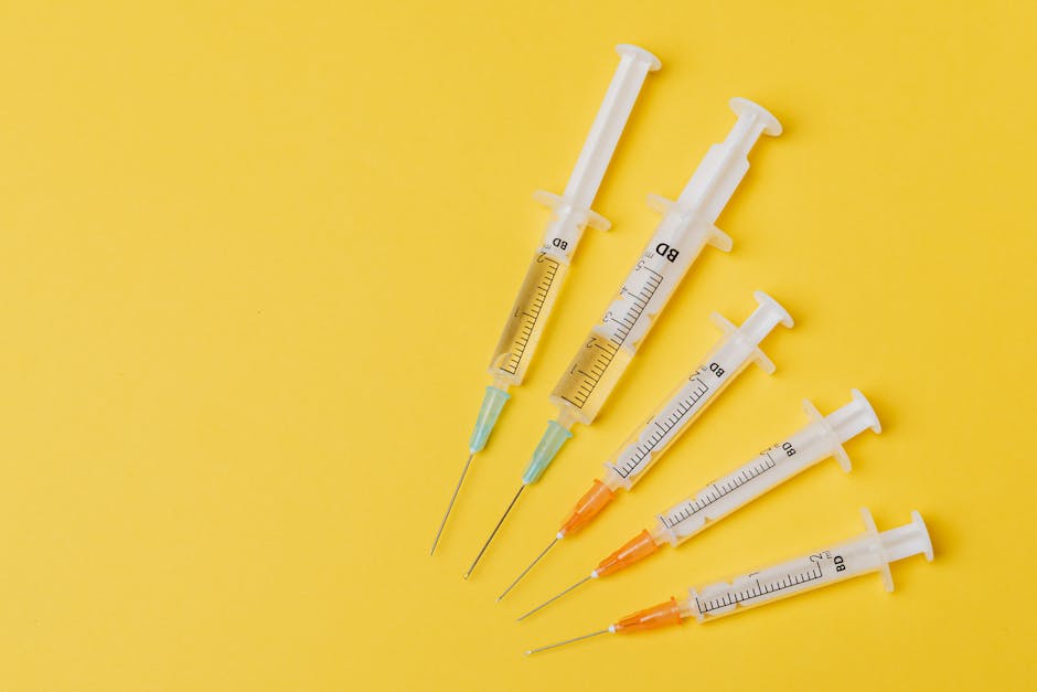 Overhead view of five syringes arranged on a yellow background.