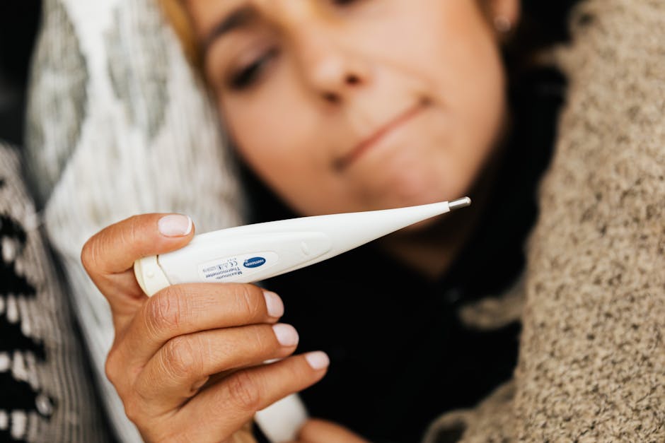 Close-up of a woman holding a digital thermometer, feeling unwell.